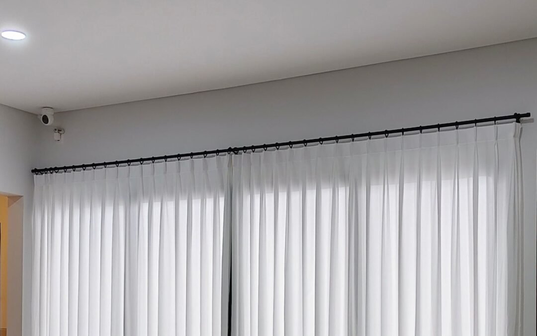 Rel gorden black doff warna hitam dengan vitrase putih lipit membentang di ruangan minimalis
