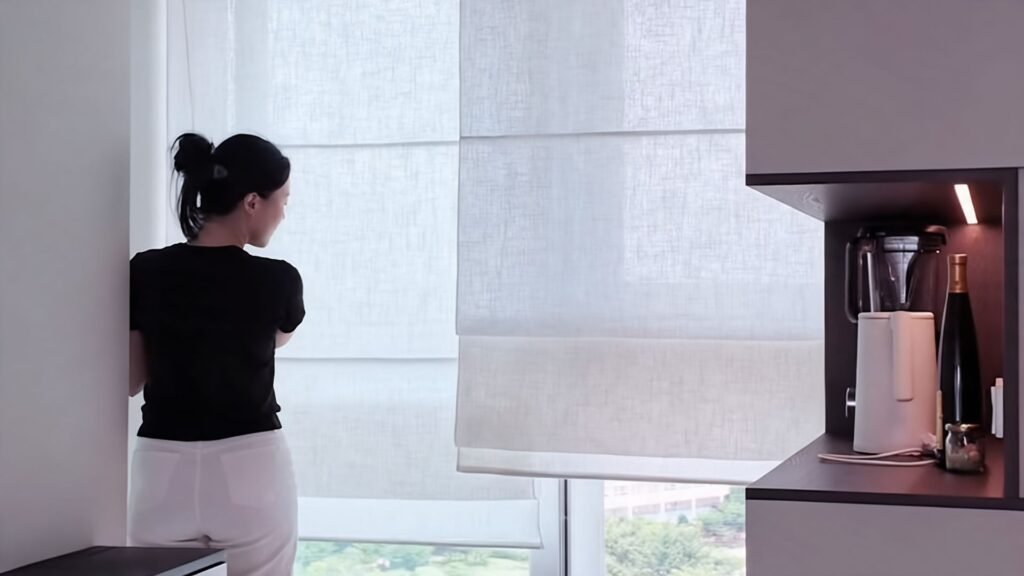Roman shade blinds elegan linen putih model lipatan datar pada jendela kaca tinggi, satu panel dinaikkan sebagian