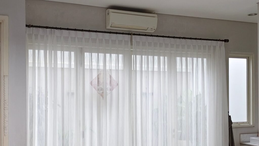 jual vitrase model kawat S / Vitrase putih bermotif garis halus dengan lipatan plisket yang digantung pada ring rel bulat hitam di depan pintu kaca