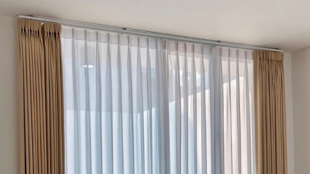 Rel gorden kotak aluminium putih dengan gorden krem dan rel vitrase putih pada jendela